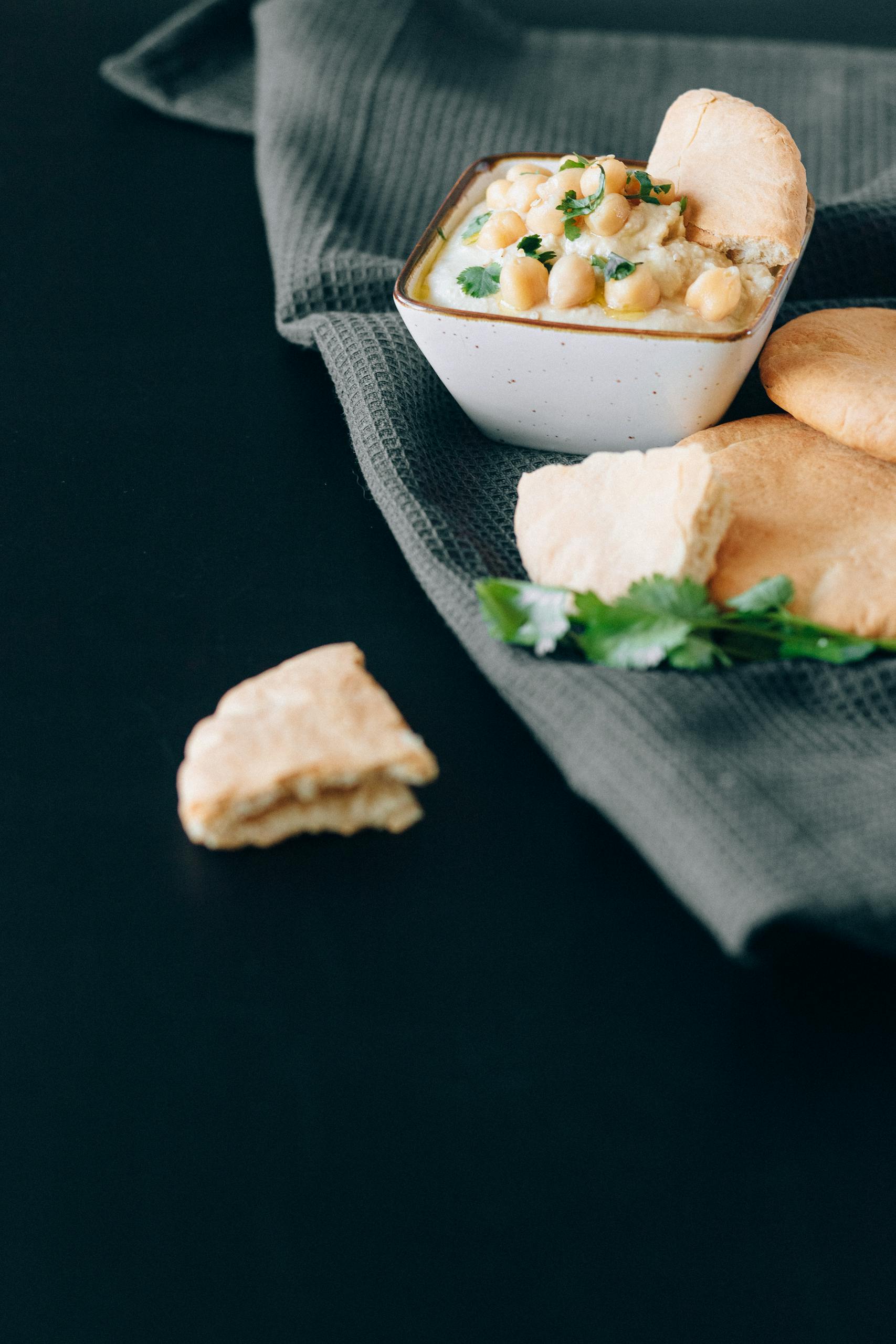Appetizing hummus with pita bread on a dark background, highlighting Mediterranean flavors.